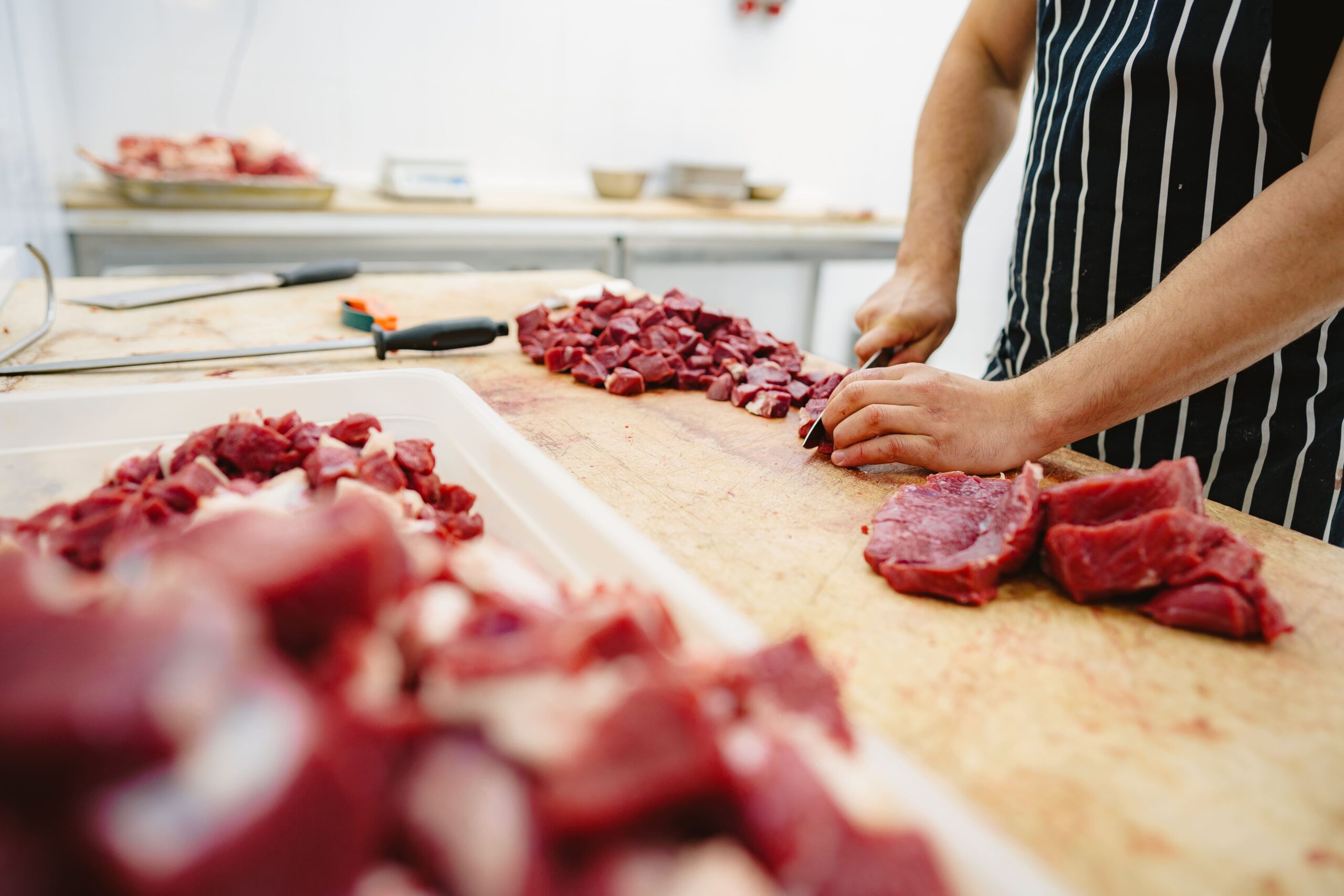 butcher-cutting-slices-of-raw-meat-on-wooden-board-2023-11-27-05-11-33-utc