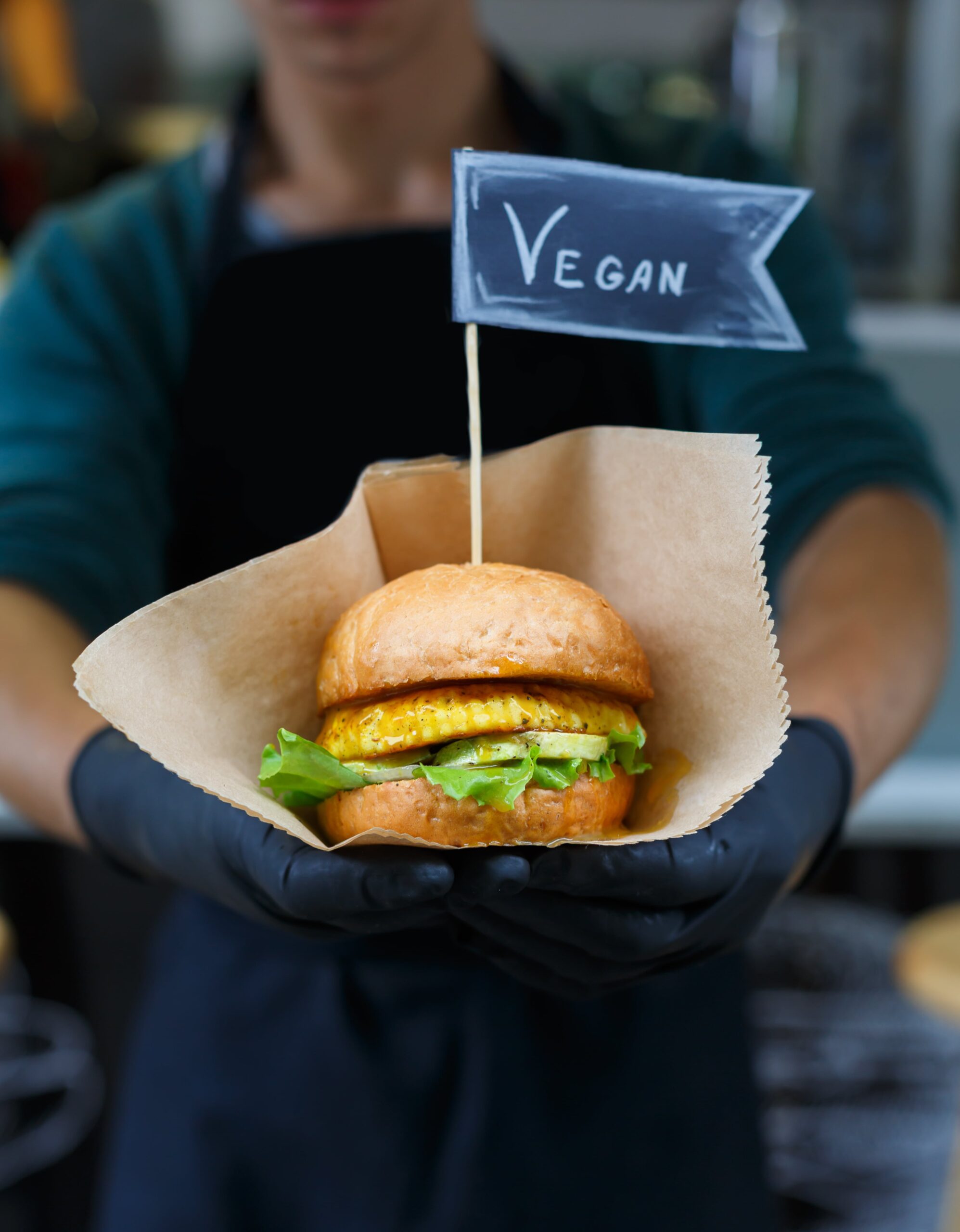 vegan-snacks-burger-with-text-label-in-hands-2023-11-27-05-17-47-utc-min